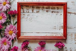 pink chrysanthemums are placed on a white wooden background with space for text and a frame photo