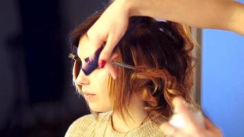 Young stylist girl makes hairstyle to a lady in hair studio video