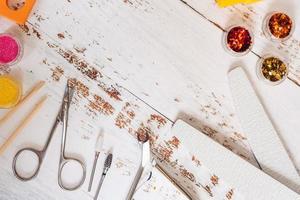conjunto de herramientas de manicura y esmaltes de uñas sobre un fondo de madera blanca. con espacio para tu texto foto
