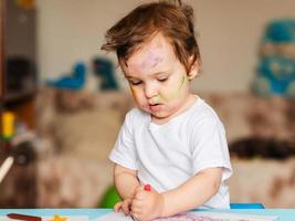 Happy little boy draws with colored pencils in an album photo