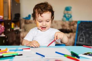 A happy cheerful child draws with a felt tip pen in an album using a variety of drawing tools. photo