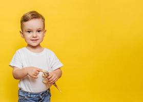 Cute laughing little boy on a yellow background with a dinosaur toy in his hands. Copy space. photo