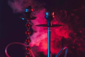 hookah bowl, shisha and coals on a smoky black background with colored lighting photo