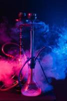 cachimba de moda con una nube de humo sobre un fondo negro con brillo rojo y azul foto