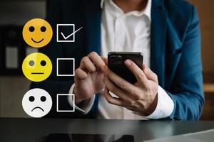 Customer service evaluation concept. woman Show face smile emoticon show on virtual screen from hand.looking at smart phone, tablet and laptop photo