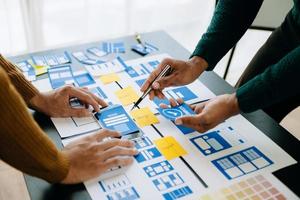 UX developer and ui designer brainstorming about mobile app interface wireframe design with customer breif and color code at office. photo