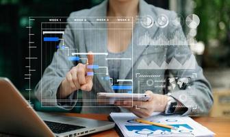 Businessman hand Project manager working and update tasks and Gantt chart scheduling virtual diagram.with smart phone, tablet and laptop in office. photo