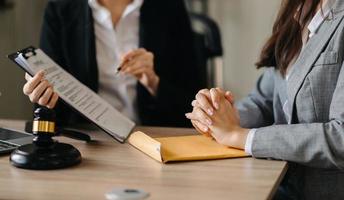 mazo de juez con escalas de justicia, negocios y abogado o consejero consultando y discutiendo documentos contractuales con computadora portátil y tableta en el bufete de abogados en la oficina. foto