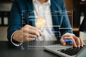 Businessman holding and putting lightbulb on coins stack on table for saving energy and money conceptIdea saving energy and accounting finance photo