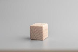 Simple empty wooden dice, one blank cubes made of wood with one central element, gray background. Copy space, logo space in the middle. photo