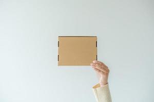 Woman hands carrying brown cardboard box. Concept of using recycle paper box. photo