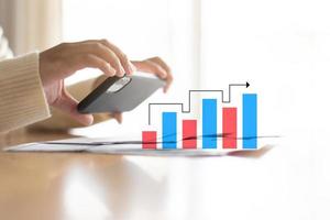 Woman using phone scan bills with bar graph showing trend of expenses photo