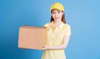 Image of young Asian delivery woman on blue background photo
