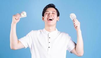 Young Asian man holding money on background photo