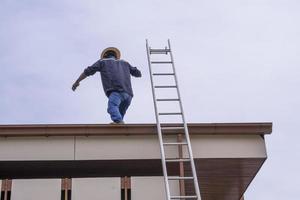 equipo de trabajadores constructores trabajando caminando en el techo para instalar la parte superior del techo de la celda solar. escaleras altas de aluminio uso para trabajo foto