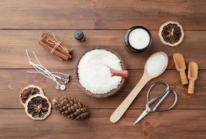 ingredients for candle making , soy wax flakes, candles, cinnamon wicks and wooden spoons on wooden background photo