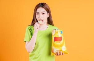 Photo of young Asian girl eating snack on background