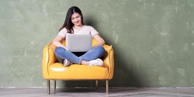 Image of beautiful young Asian woman sitting on yellow armchair photo