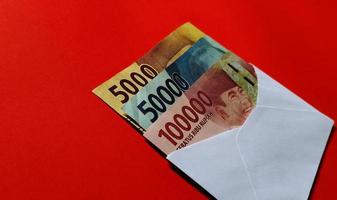 Indonesian Rupiah in white envelope isolated on red background. The concept of giving angpao on Chinese New Year photo
