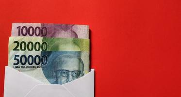 Indonesian Rupiah in white envelope isolated on red background. The concept of giving angpao on Imlek photo