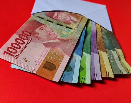 Indonesian Rupiah in white envelope isolated on red background. The concept of giving angpao on Chinese New Year photo