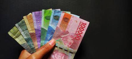 A person holding cash in Indonesian rupiah isolated on black background photo