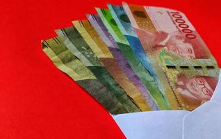 Indonesian Rupiah in white envelope isolated on red background. The concept of giving angpao on Chinese New Year photo