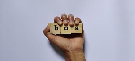 Portrait of a word BOS on wooden cubes. Conceptual business illustration photo