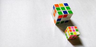 Jakarta, December 2022. Two rubik's cubes of different sizes and colors isolated on white background. Free space photo