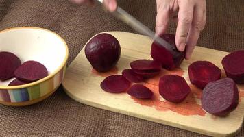 manos de mujer cortando remolacha en una tabla de cortar de madera. concepto de cocina casera. ensalada o cualquier plato vegetariano. video