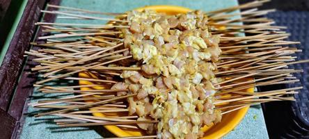 Some skewers of seasoned raw chicken, ready to be grilled photo