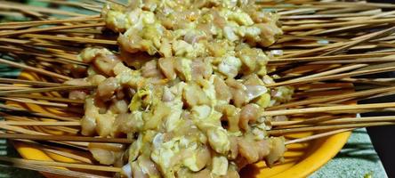 Some skewers of seasoned raw chicken, ready to be grilled photo