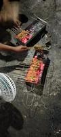 A few skewers of raw, seasoned chicken skewers and being grilled, ready to be served photo