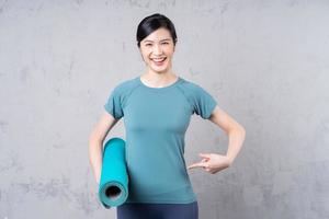 image of young Asian woman holding yoga carpet photo