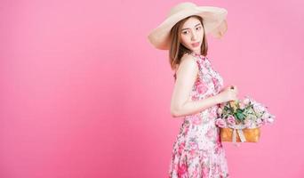 foto de una joven asiática con un vestido de flores de fondo rosa