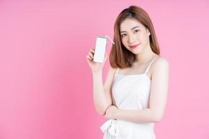imagen de una joven asiática sosteniendo un cartón de leche con fondo rosa foto