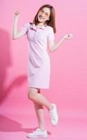 Full length photo of young Asian girl on pink background