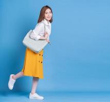 Full length photo of young Asian woman on blue background