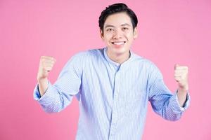 Portrait of young Asian man on pink background photo