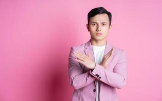 Portrait of young Asian man wearing pink suit posing on background photo