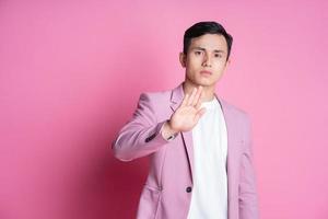 Portrait of young Asian man wearing pink suit posing on background photo