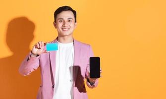 Image of young Asian man holding bank card, atm card on background photo