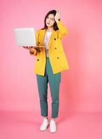 Full length image of young Asian bussinesswoman holding laptop on background photo