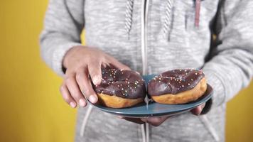 recoger a mano donuts de chocolate en un plato