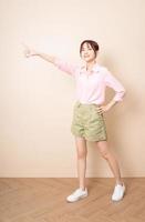 Full length photo of young Asian woman standing on background