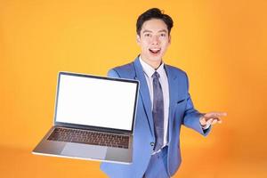 Image of young Asian businessman using laptop on background photo