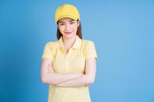 Image of young Asian delivery woman on blue background photo