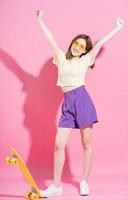 Photo of Asian teenager girl with skateboard on pink background