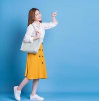 Full length photo of young Asian woman on blue background