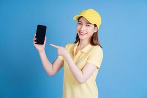 Image of young Asian delivery woman on blue background photo